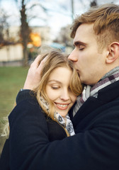 young man embracing and tenderly kissing his girlfriend, feeling comfortable together.