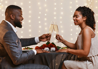 Happy afro couple having festive dinner at fancy restaurant