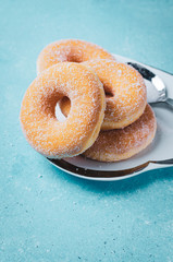 Donuts on white heart shape plate with sugar on turquoise backround+