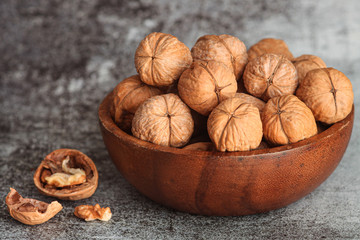 Walnuts in a wooden bowl on a gray background