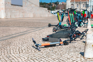 many modern electric scooters for rent in a city parking lot in the Portuguese capital on a sunny spring day