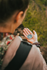 Women check direction at the compass in her hand to find right hiking path
