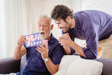 elder exciting and wow when opening gift box present from his son in living room.