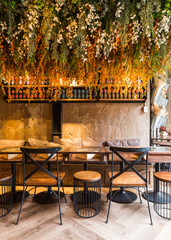 Dining table sets decorated with table, wooden chairs, green plant and flowers. Modern interior restaurant atmosphere. Tropical design.