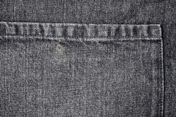 Dark denim material, texture. Closeup of denim fabric apron with part of the pocket. Grainy pattern of textured cotton fabric. Flat denim surface. Grey jeans, background. Part of the grunge curtain.