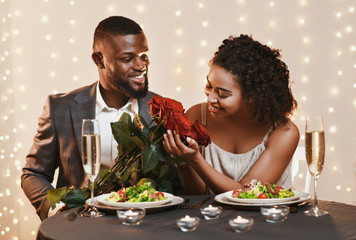 Handsome afro man giving beautiful flowers to his woman