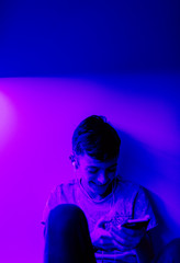A young boy listening to music in his bedroom with LED lights on.