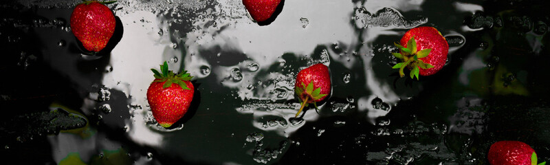 Banner of Whole strawberries on black background with water drops. Wet strawberries