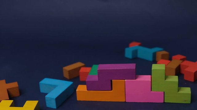 Closeup Slow motion. Hand holding piece of wooden block puzzle. wood cube stacking. Concept of complex and smart logical thinking. on a black background