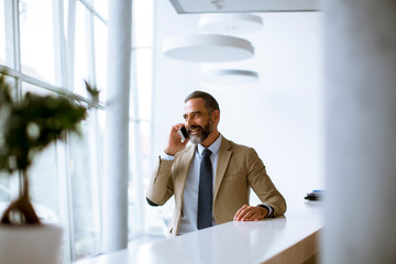 Senior businessman using mobile phone in modern office