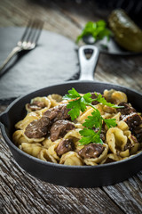 Italian pasta shells with beef sauce in cast iron pan.