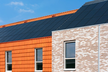 Solar collectors on a roof of a brick facade clad and roof tiles facade clad building. Space for text.