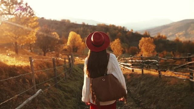 Outdoor autumn fashion portrait of young beautiful confident woman walking at sunset in mountain landscape.