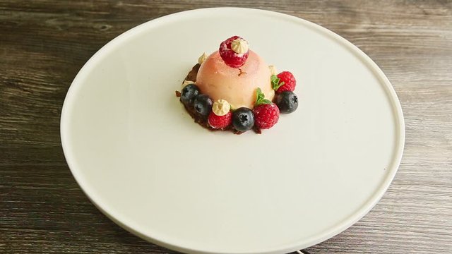 zoom in at icing dessert trendy decorated with berries rotates on plate