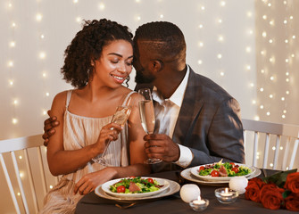 Romantic black couple toasting with champagne at restaurant