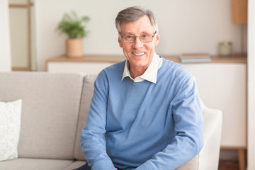 Smiling Senior Gentleman Sitting On Couch At Home