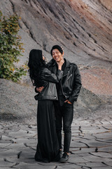 Fototapeta na wymiar An Asian couple in love in black leather clothes walk in nature among the trees. Style, fashion, love
