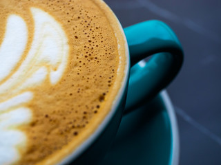 Close-up of foam in a cappuccino. Drawing on coffee, the bubbles in the foam of coffee. Green coffee mug on a black table