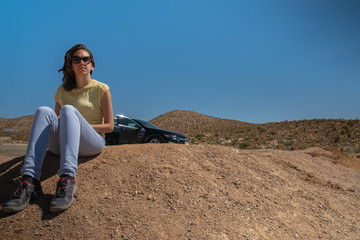Fototapeta na wymiar Young girl sit in thee desert during a road trop, mojave desert