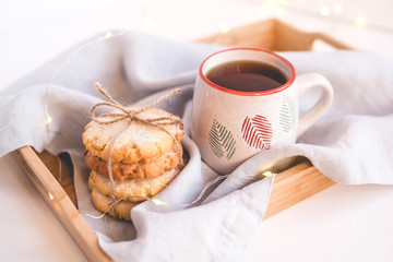 Fresh cookies and cup of tea on a wooden tray.