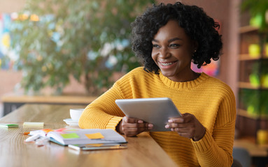 Smiling african girl using digital tablet in cafe