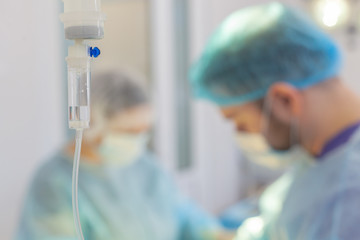 Hospital. Surgeon operates in the operating room. Dropper on a blurry background with operating doctors