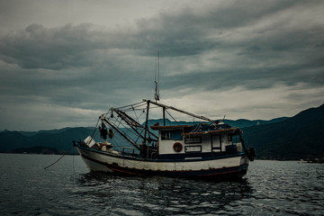 Old boat on the high seas. Cloudy, rainy weather, gray skies and bluish sea.