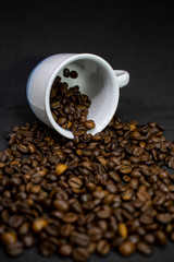 Coffee cup with grains against dark background. Close-up with copy space for your text.