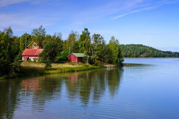 Fototapeta na wymiar Picturesque lake with wooden houses on the shore, typical nature of Finland.