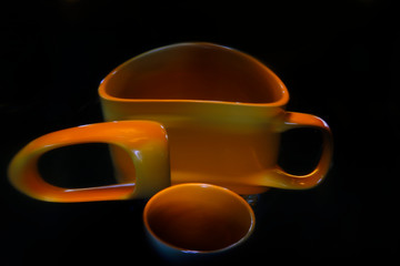 A mug and its reflection in a crooked mirror, painted with multi-colored light