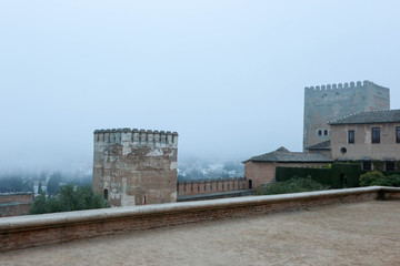 View of city Granada in morning fog and tower of the Alhambra citadel