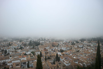 aerial view of granada covered by mist from alhambra citadel wall