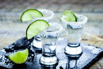 Party in bar with tequila, salt and lime on wooden table