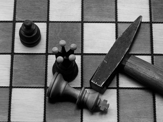 Brutal Checkmate: A Hammer Lying Next To A Defeated White King On A Wooden Chess Board, Monochrome