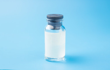 Medical glass bottle with copy space, on a blue background with syringes. Selective focus. Copy...