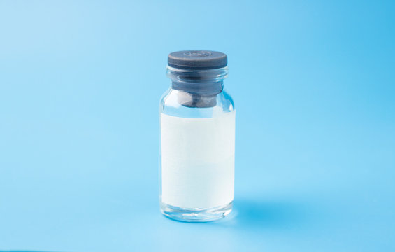 Medical glass bottle with copy space, on a blue background with syringes. Selective focus. Copy space