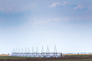 Fototapeta premium Center pivot irrigation - radial sprinkler system irrigation in action on agricultural field at sunny summer day. The hot air flows over the hot field. Agricultural machinery theme.