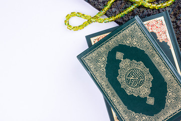 Holy Quran with arabic calligraphy meaning of Al Quran and tasbih or rosary beads over white background, copy space.