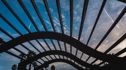 Fototapeta na wymiar Detail of a pergola wave shaped with a cloudy sky of in the background