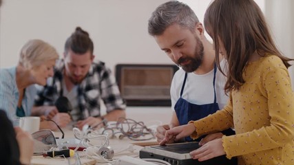 A group of people at repair cafe repairing household electrical devices.