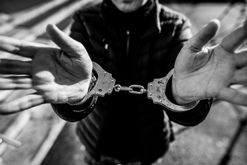 Monochrome shallow depth of field (selective focus) image with the handcuffed hands of a man.