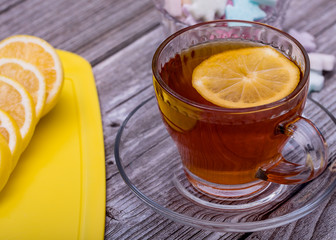 Cup of tea with lemon on a wooden table. Morning tea with lemon and pastries.