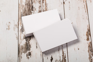 Mock up blank white business cards on a light rustic natural aged wooden background.