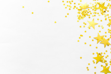 Gold confetti and stars and sparkles on a light background. Top view, flat lay. Copy text. Bright and festive background. For Christmas, New Year, Mother's Day.