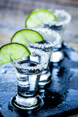 Bar set with shots, fresh lime and salt on wooden background