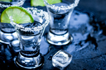 Alcohol party with tequila, ice and salt on black background