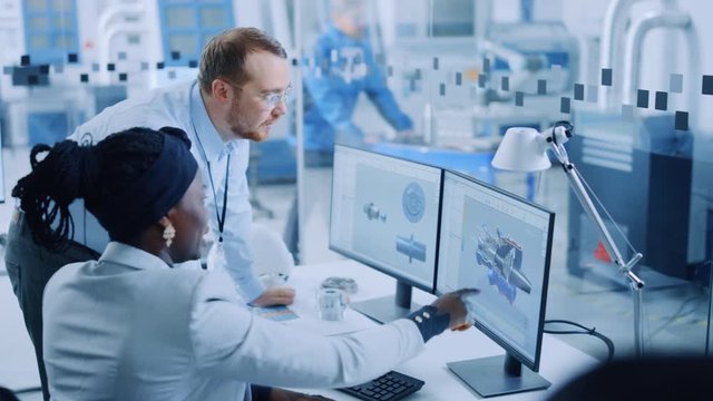 Modern Factory: Male Project Supervisor Talks to a Female Industrial Engineer who Works on Computer. They use CAD Software for Design Zero-Emissions Engine. Working High-Tech Industrial Facility