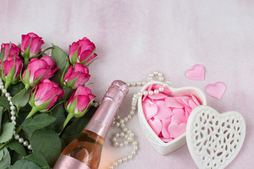 a bottle of champagne, hearts in a casket, a bouquet of pink roses, pearl beads 