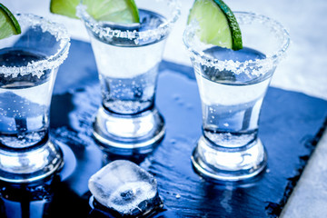 Alcohol shots with ice, lime and salt on gray stone background
