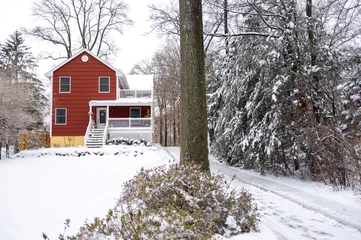 Fotobehang red suburban house in snowy winter landscape © Michele